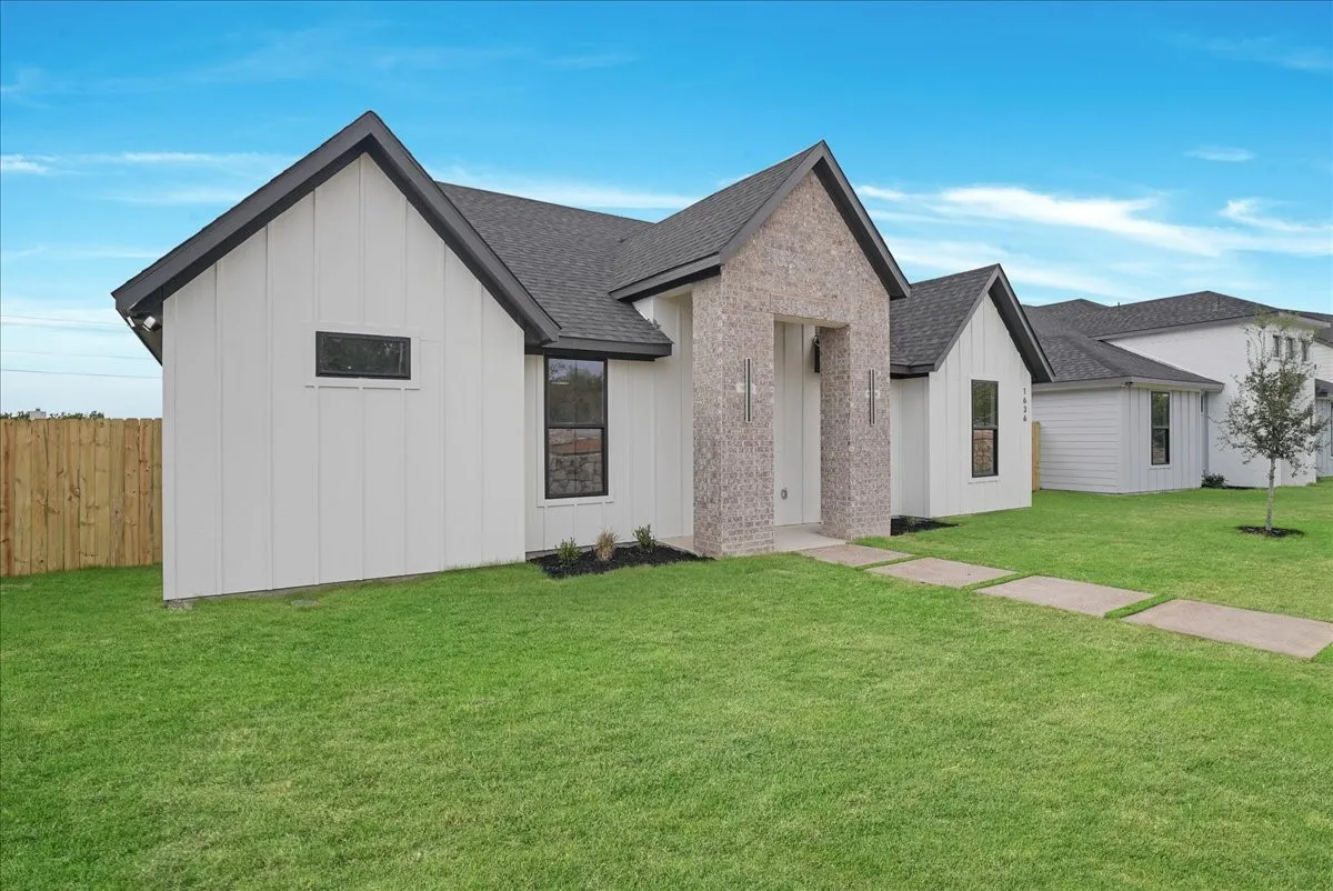 Contemporary exterior with board-and-batten siding, brick façade accents, and a dark shingle roof