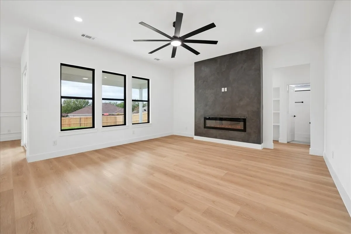 Wood-finish flooring throughout, featuring a modern electric fireplace with a textured accent wall