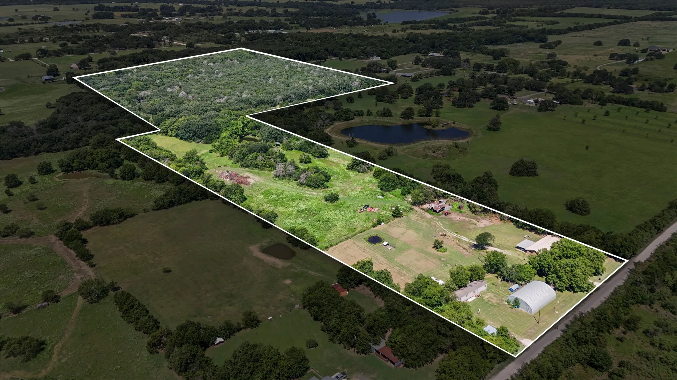 Expansive rural property featuring a mix of open fields and densely wooded areas