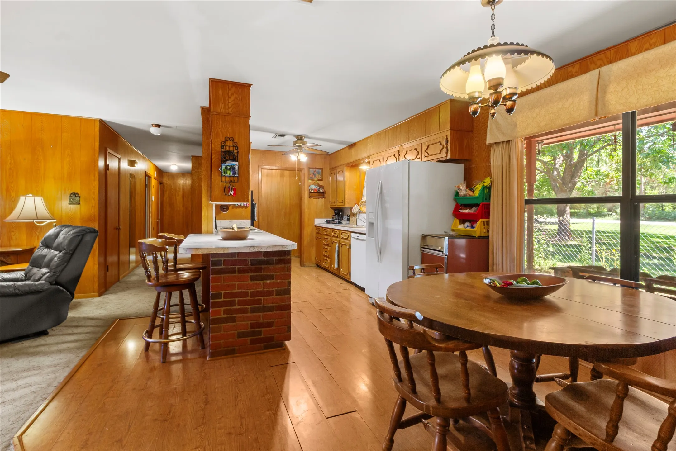 Warm wood cabinetry and rich wood-finish flooring define this expansive kitchen and dining area