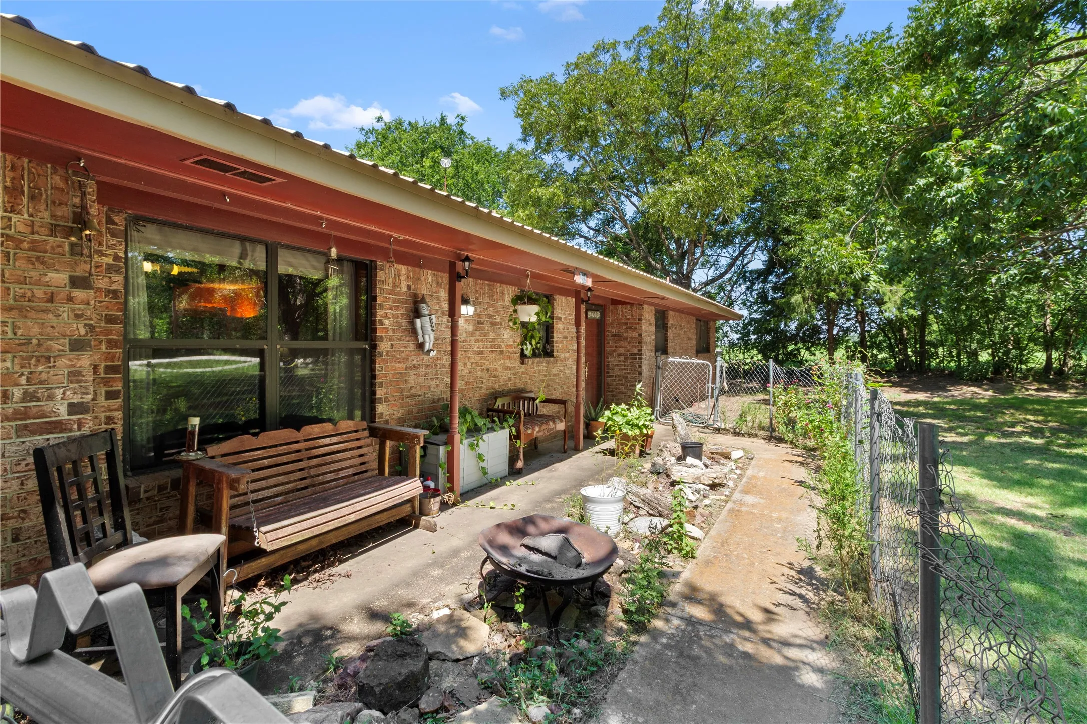 Charming brick residence with a covered patio featuring wood-beam construction and large glass doors opening to the backyard