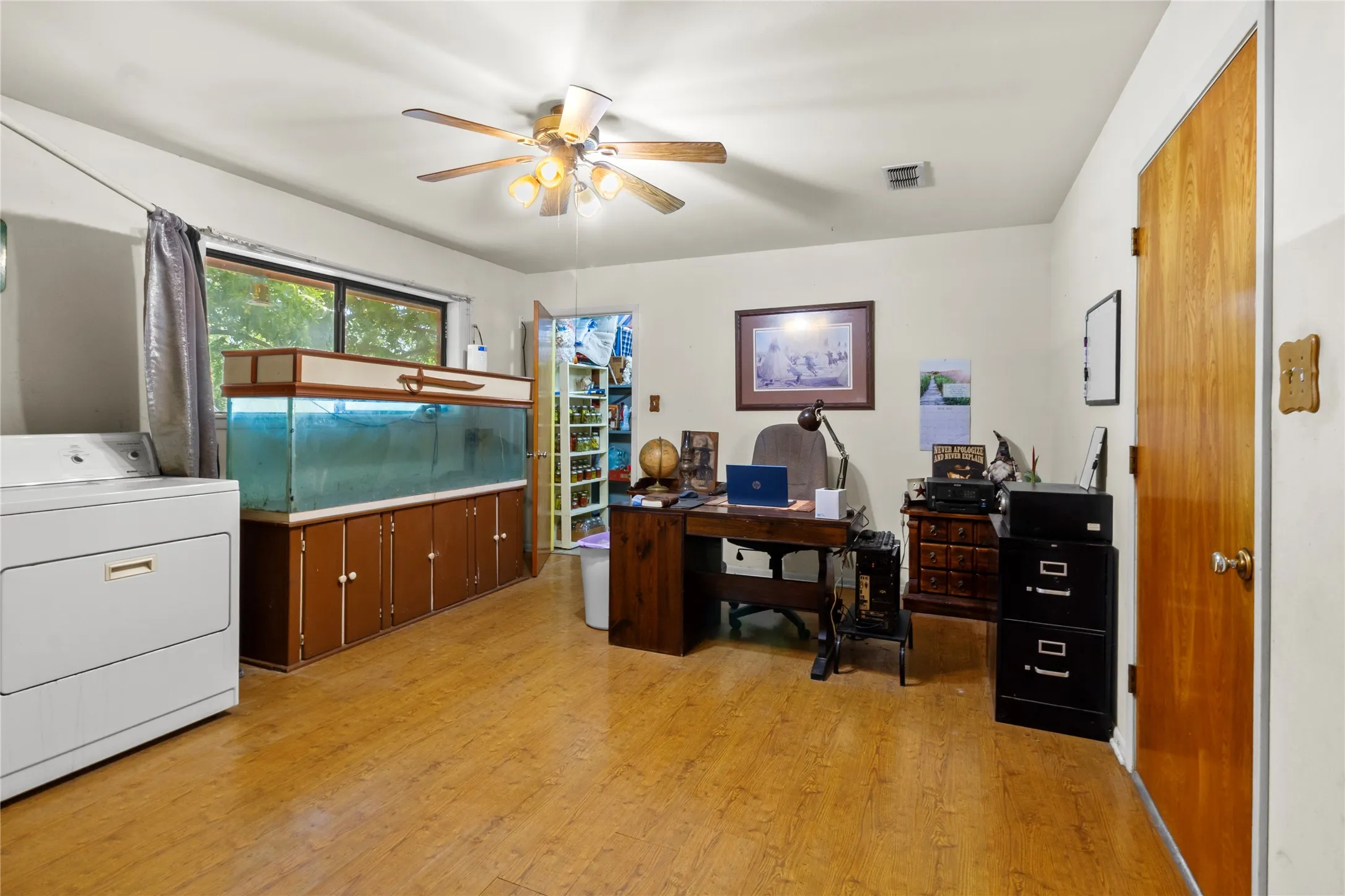 Spacious room featuring wood-finish flooring, a l ceiling fan with integrated lighting, and a large window