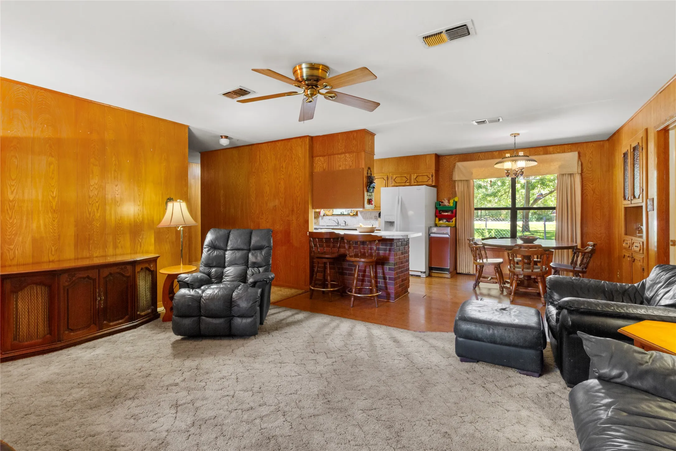 Open-concept living area featuring wood paneling, a ceiling fan, and recessed lighting