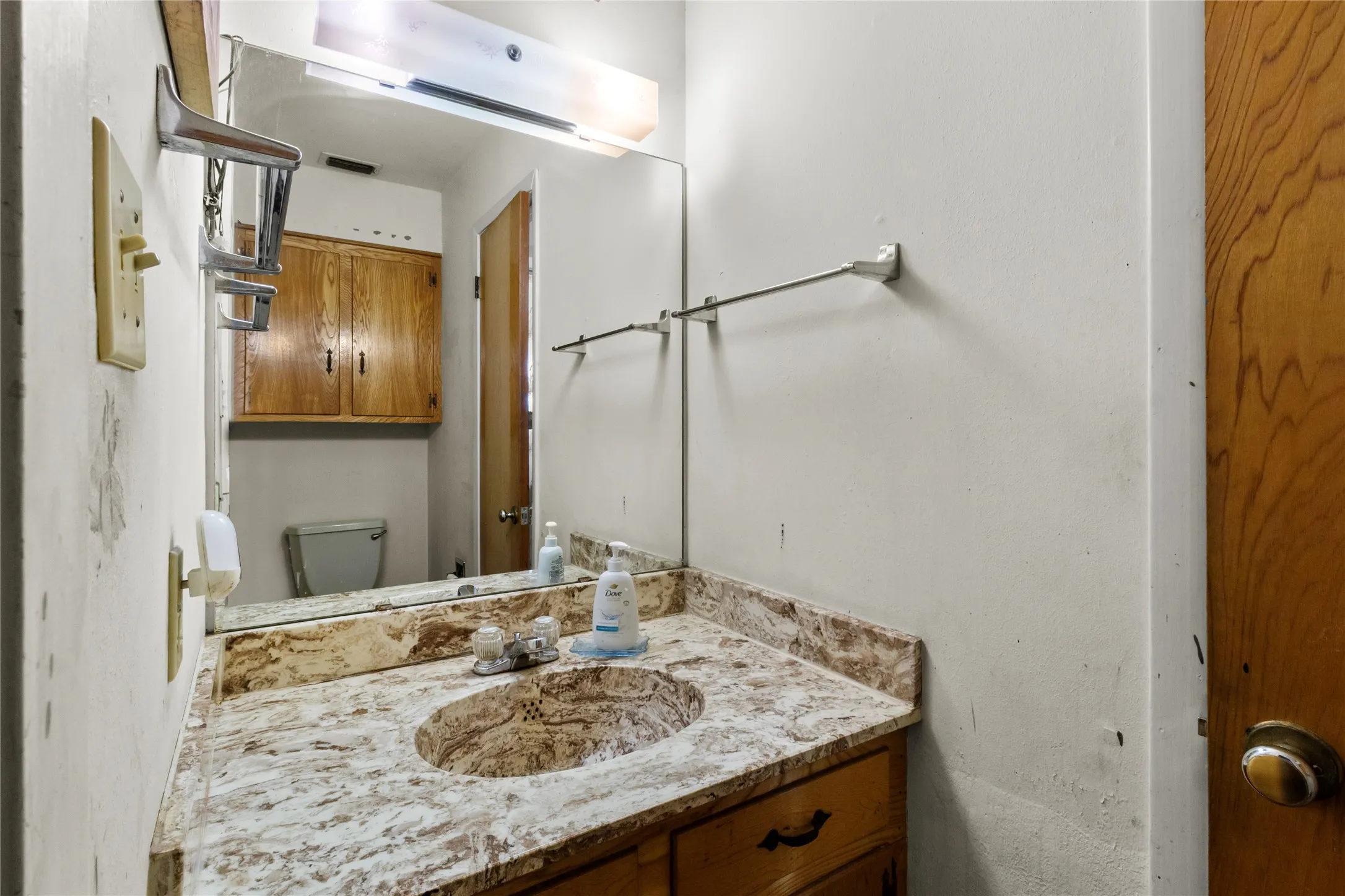 Bathroom featuring a granite-topped vanity with an integrated sink, chrome vessel faucet, and framed mirror