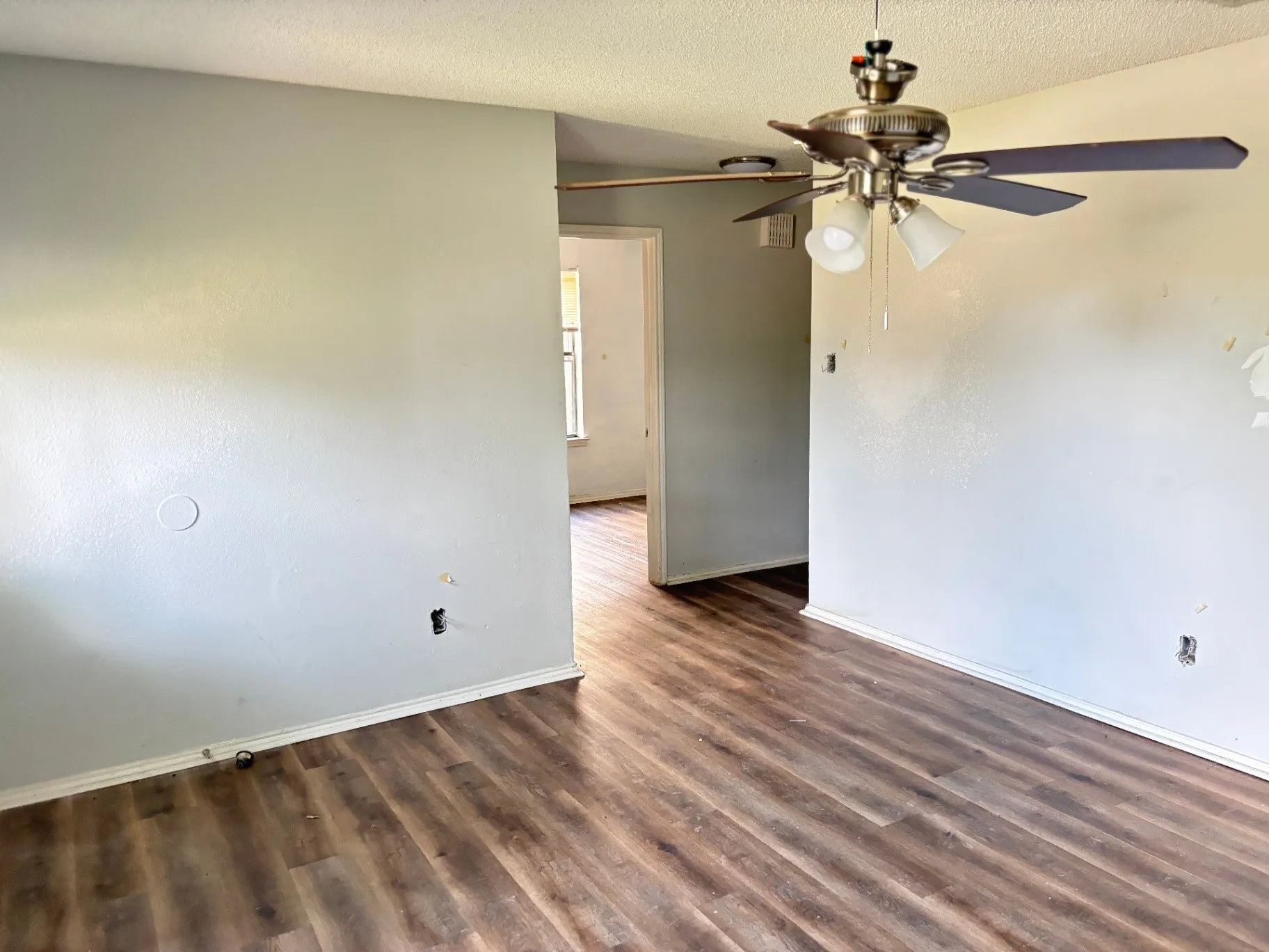 Interior space featuring wood-finish flooring, light-toned walls, and a ceiling fan with integrated lighting
