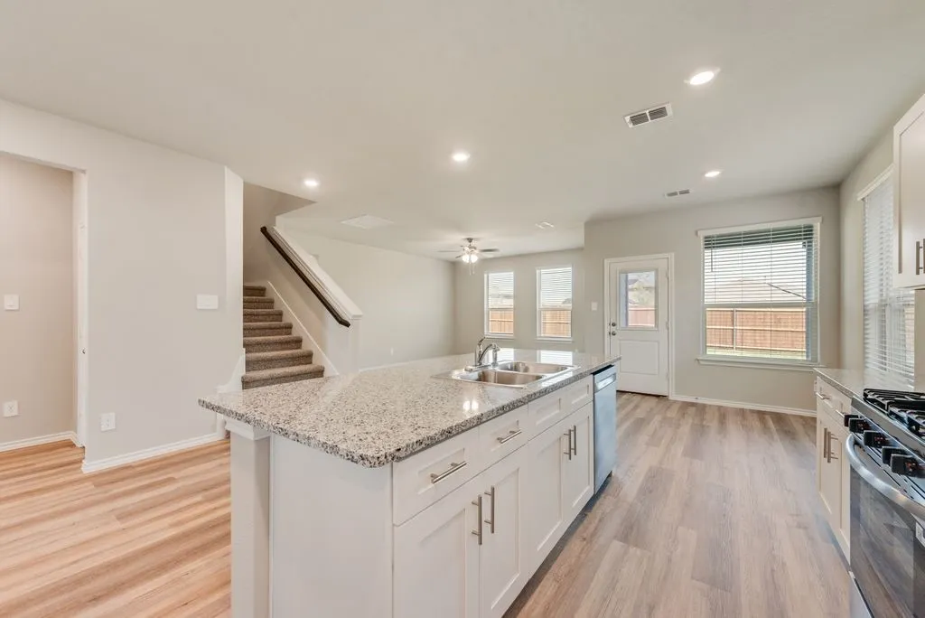 Chef's kitchen featuring white cabinetry, granite countertop island with seating, stainless steel gas range, recessed ceiling lighting, and wood-finish flooring