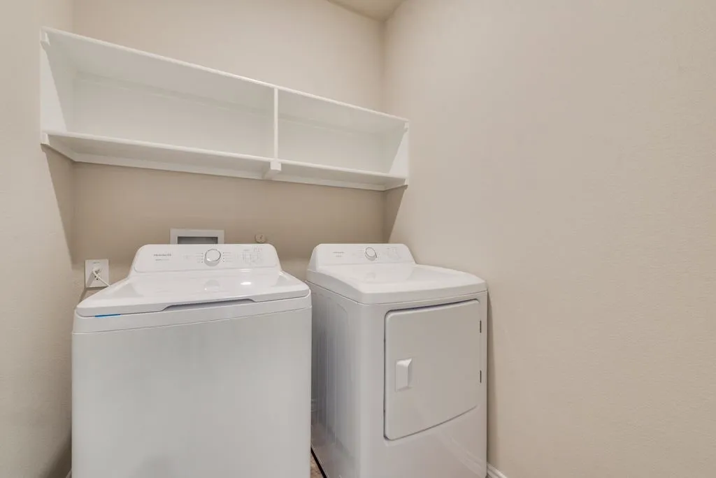 Dedicated utility space featuring overhead open shelving for storage