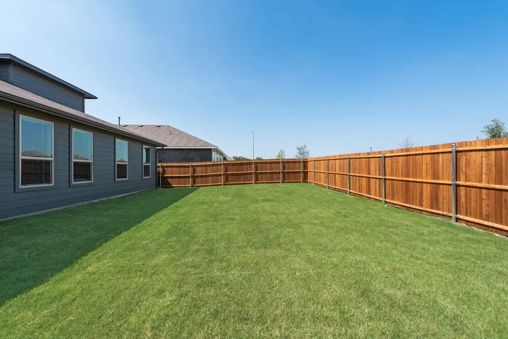 Expansive backyard featuring a professionally installed wood privacy fence and lush, manicured lawn