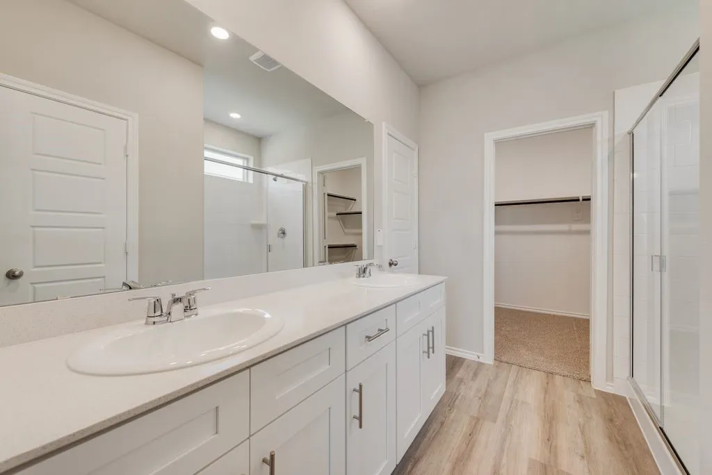 Contemporary bathroom featuring a double vanity with white cabinetry and a light-toned countertop