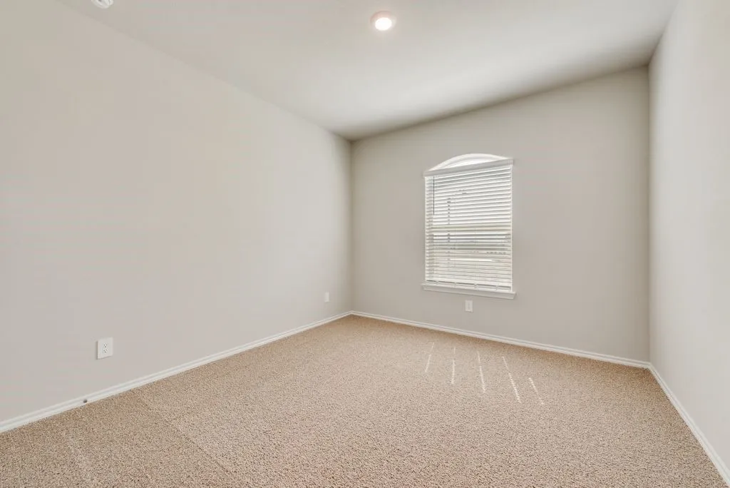 Neutral tone walls, vaulted ceiling with recessed lighting, and beige carpeting create an inviting atmosphere