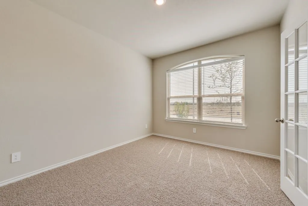 Bright and airy bedroom showcasing neutral wall finishes, recessed ceiling lighting, and expansive windows with plantation shutters providing natural light and privacy
