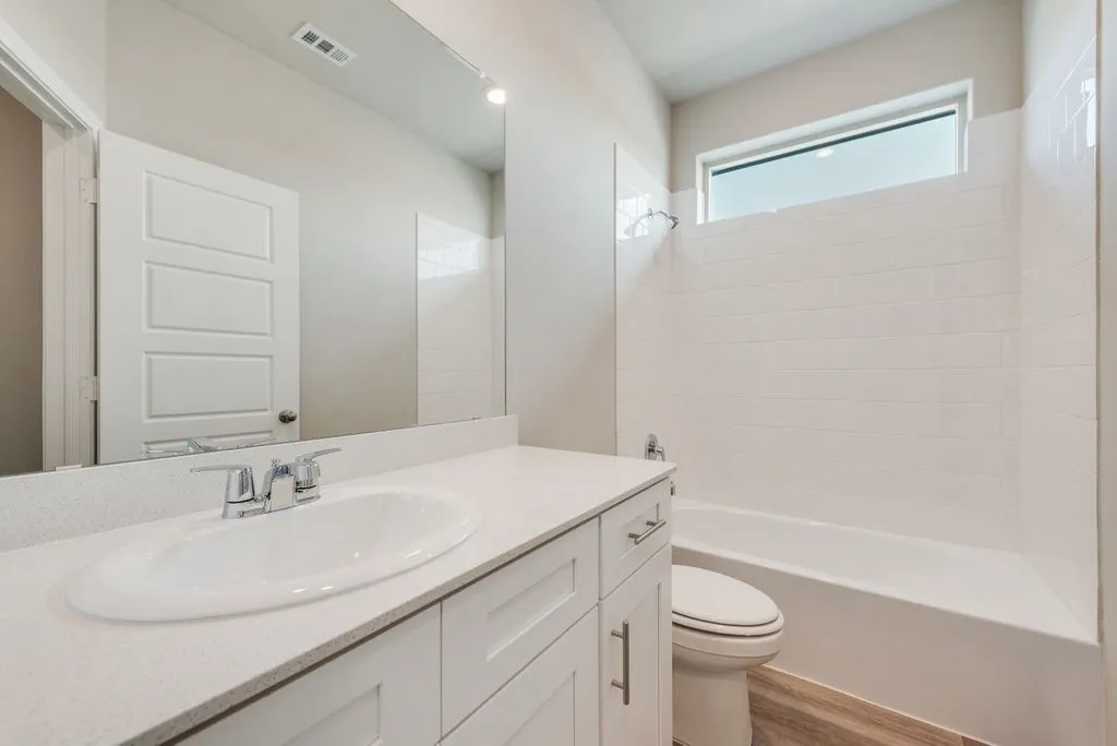 Bright, spa-like bathroom featuring a curved vanity with white cabinetry, white quartz countertop, and polished chrome faucet