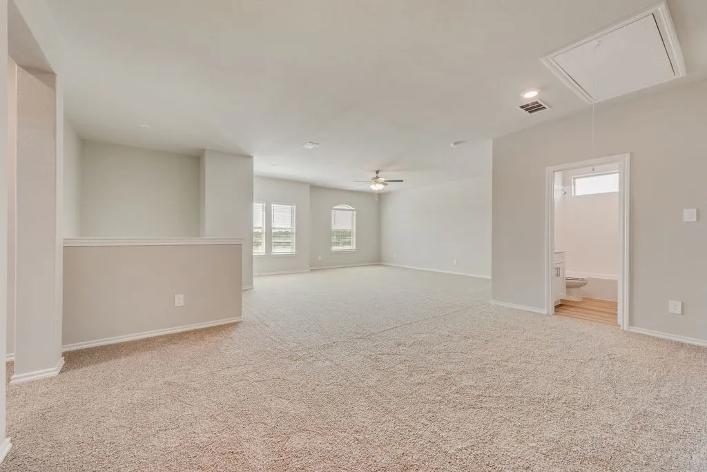 Spacious open-concept recreation room featuring neutral carpet flooring, recessed ceiling lighting, and abundant natural light from multiple windows