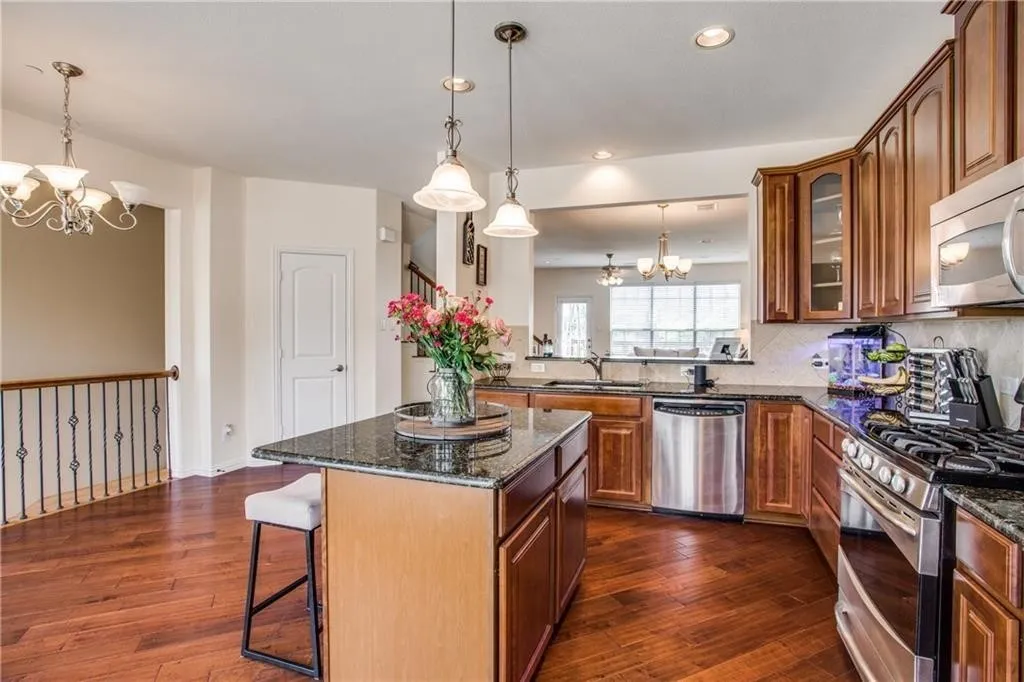 Kitchen featuring dark wood-type flooring, a sink, appliances with stainless steel finishes, and an inviting chandelier