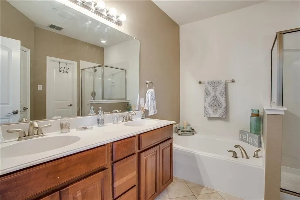 Full bath with a stall shower, a bath, tile patterned flooring, and a sink