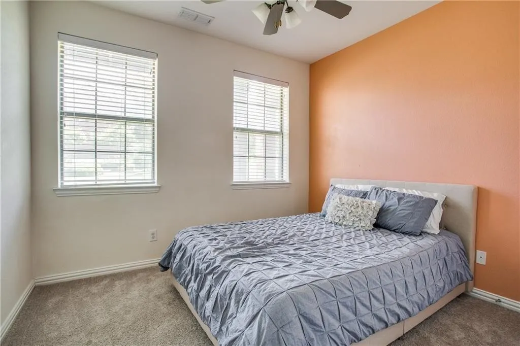 Carpeted bedroom featuring a ceiling fan, baseboards, and visible vents