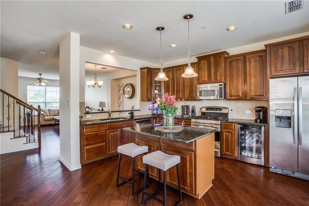 Kitchen featuring a kitchen island, beverage cooler, dark wood-style floors, visible vents, and appliances with stainless steel finishes