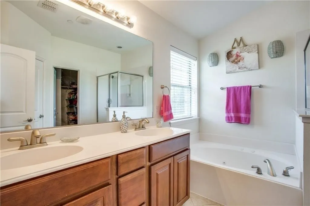 Bathroom featuring double vanity, a sink, a garden tub, and a shower stall