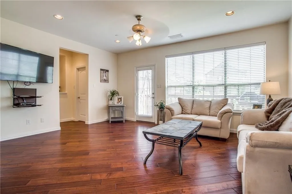 Living room with dark wood finished floors, a wealth of natural light, and a ceiling fan