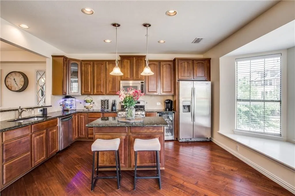 Kitchen with wine cooler, a sink, appliances with stainless steel finishes, brown cabinets, and visible vents