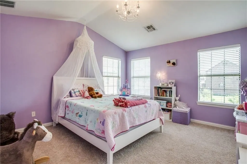 Bedroom featuring light colored carpet, visible vents, multiple windows, and vaulted ceiling