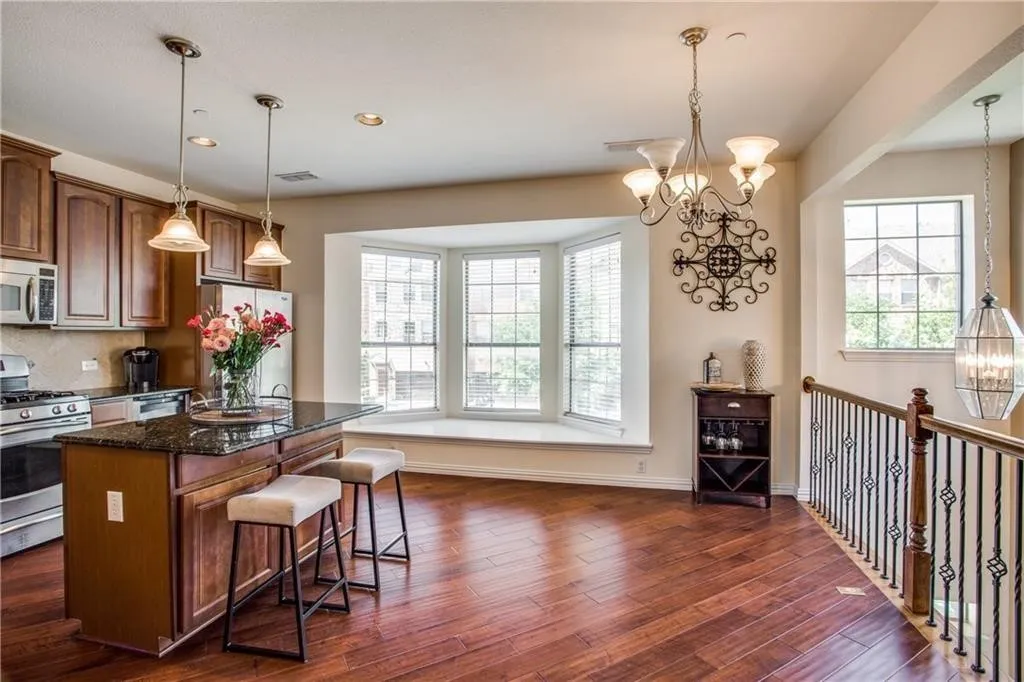 Kitchen featuring a chandelier, freestanding refrigerator, a kitchen bar, gas range, and white microwave