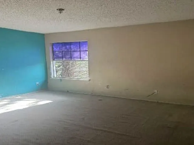 Room featuring a window, textured ceiling, and carpeted flooring