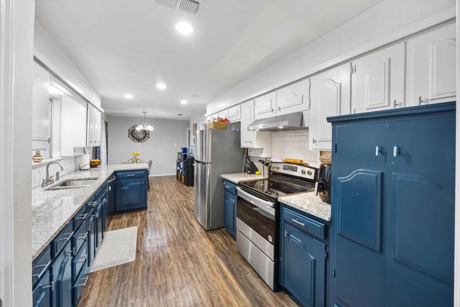 Galley kitchen featuring wood-finish flooring, light-toned countertops, subway tile backsplash, and recessed lighting