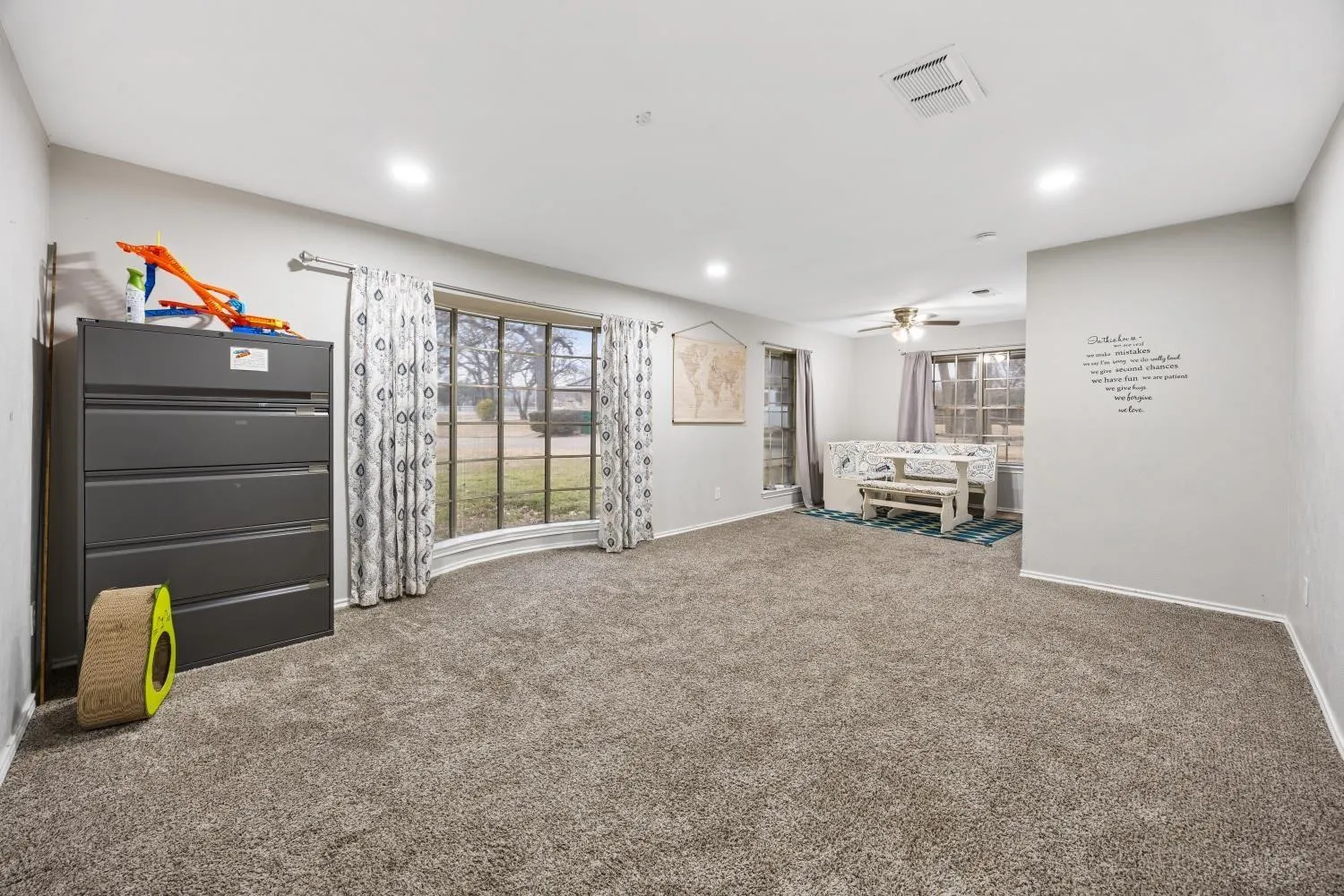 Spacious interior room featuring plush gray carpet, light gray wall paint, and recessed lighting