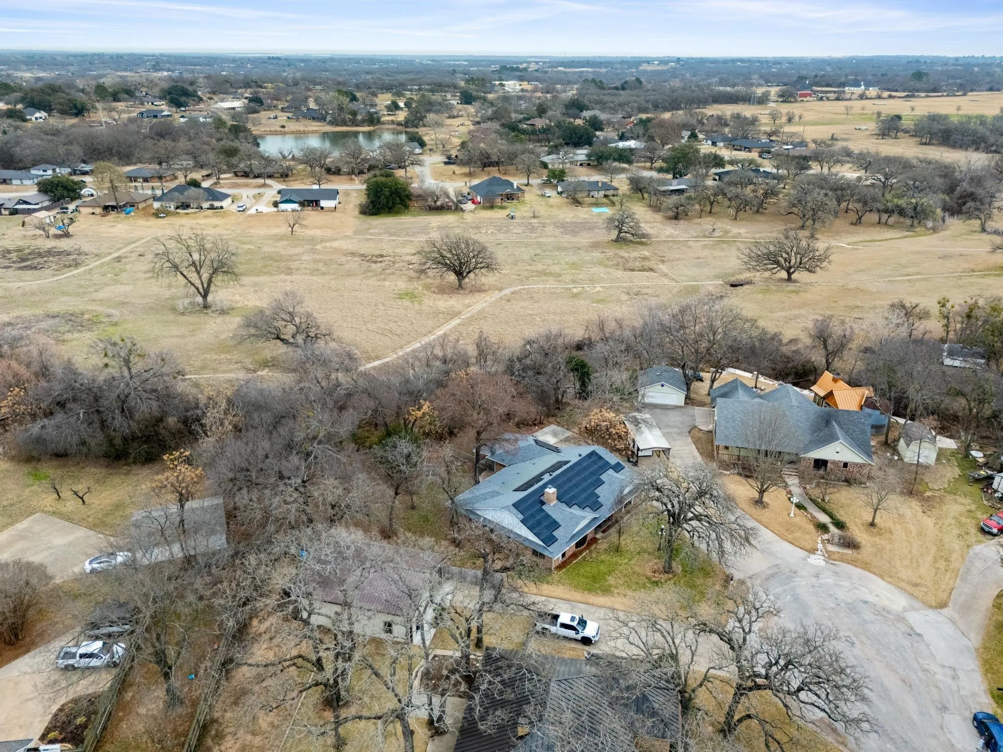 Aerial perspective showcasing a residential property with a dark shingle roof and visible solar panels