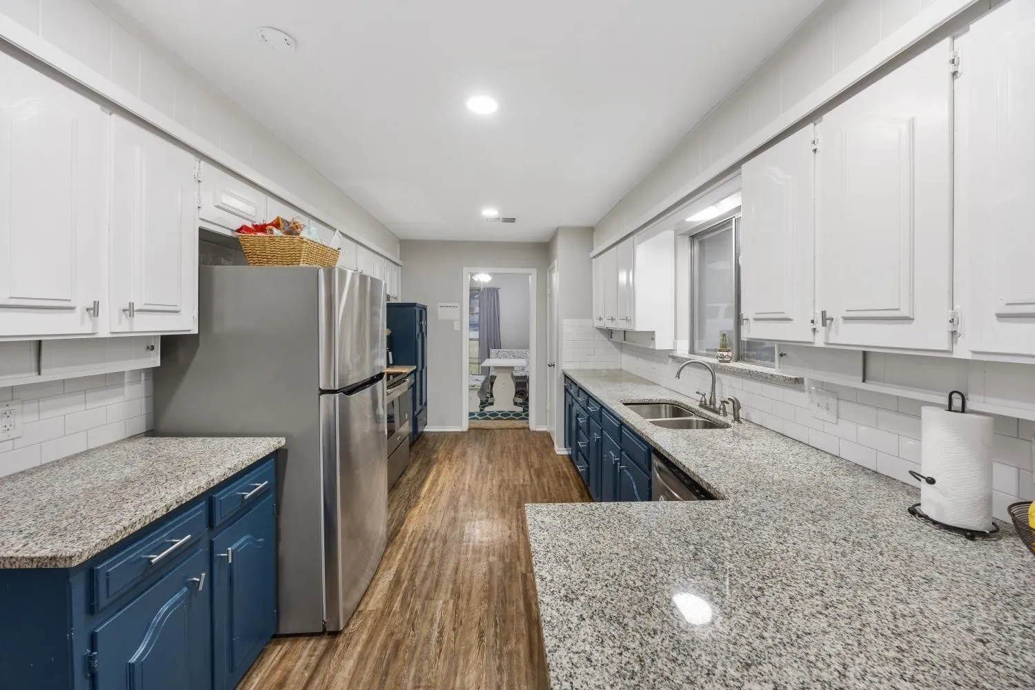 Galley kitchen featuring wood-finish flooring, light-toned countertops, and white subway tile backsplash