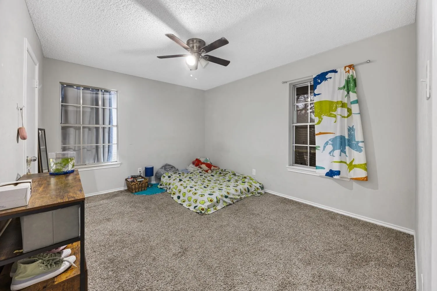 Carpeted room featuring light gray walls, two windows, and a ceiling fan with integrated lighting