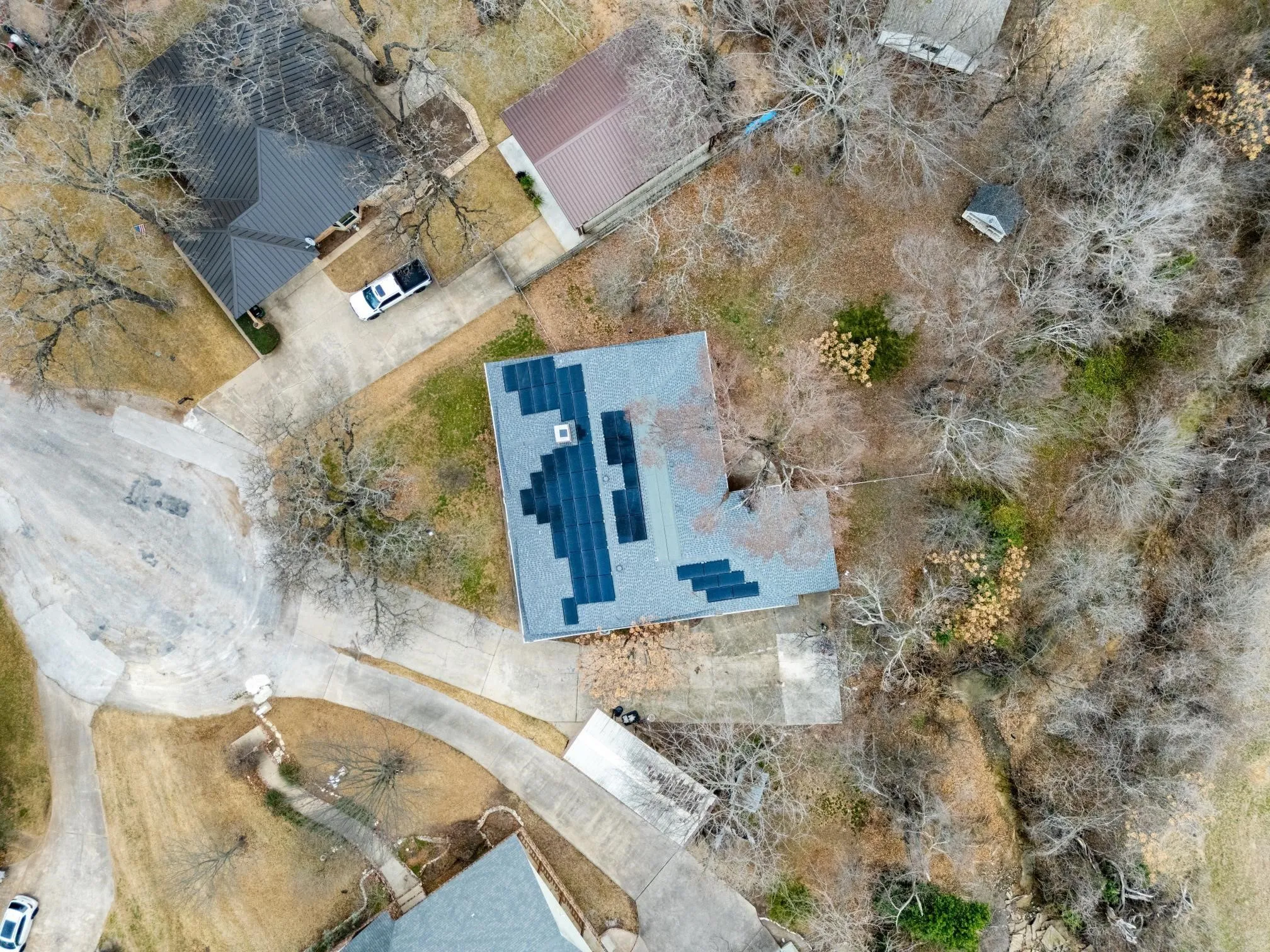 Aerial perspective showcasing a property with a grey shingle roof featuring integrated solar panels