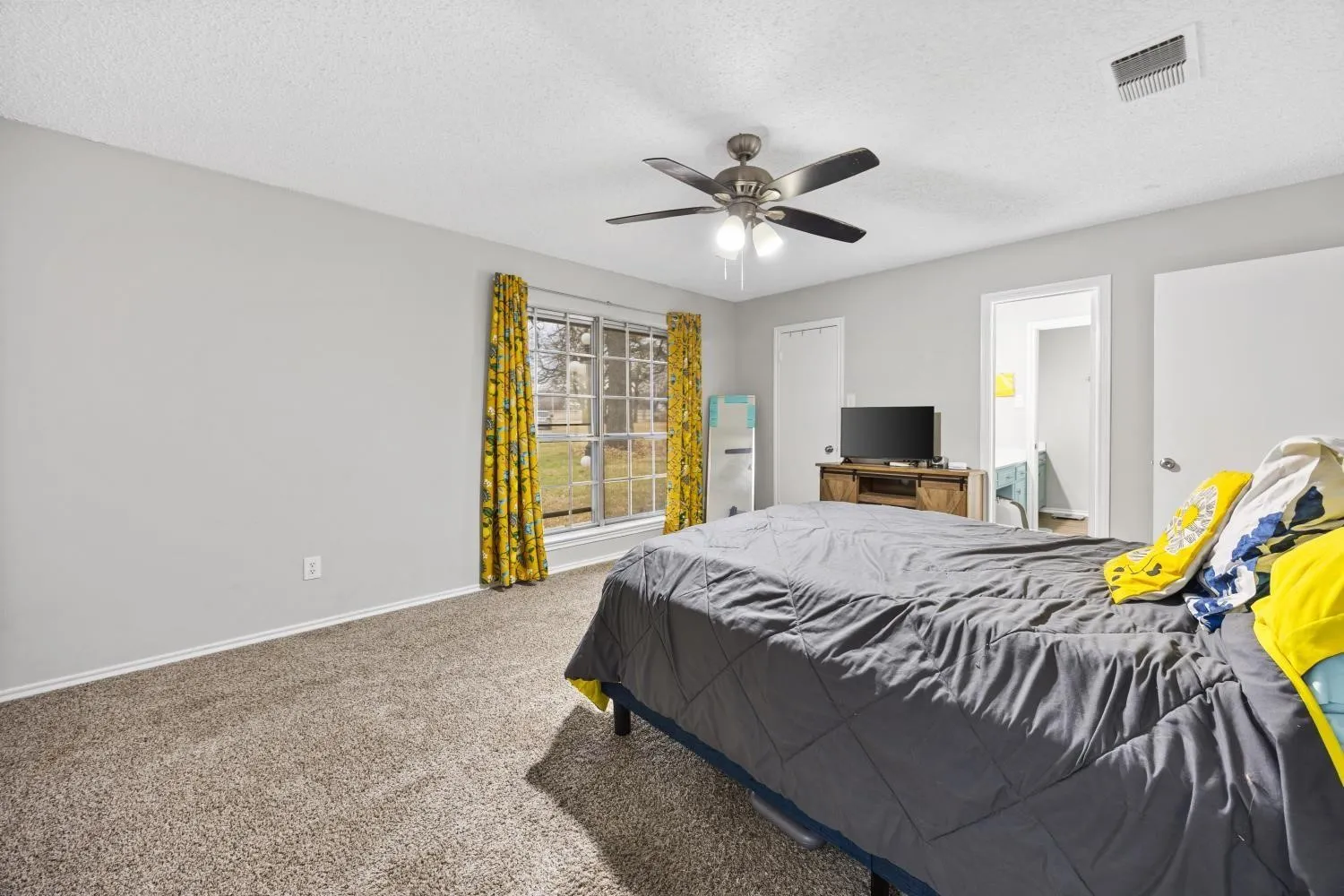 Bedroom featuring light gray wall paint, textured ceiling, and neutral-toned carpeting