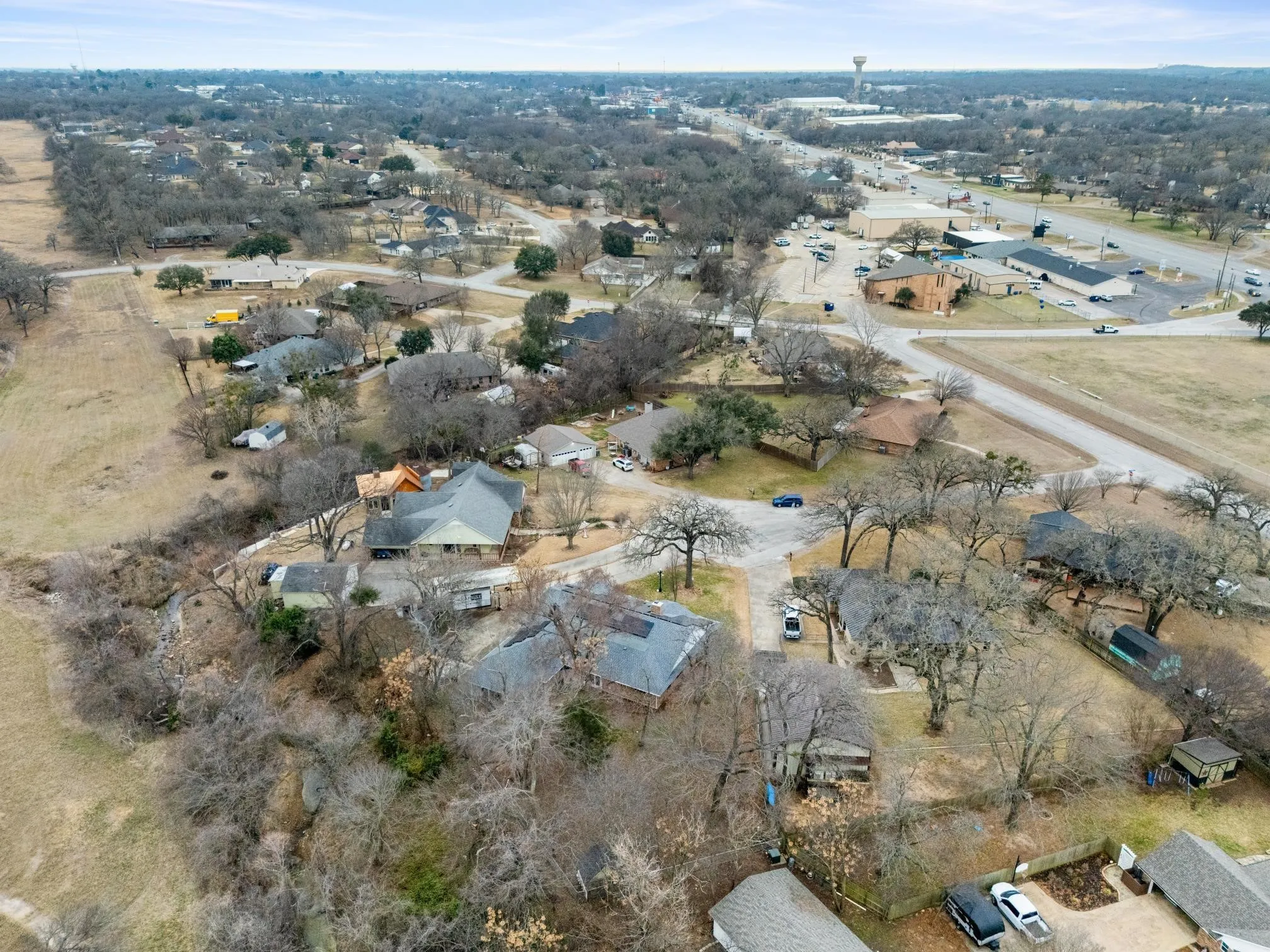 Aerial view showcasing this rural property's expansive acreage with multiple structures, mature tree coverage, and pastoral landscape
