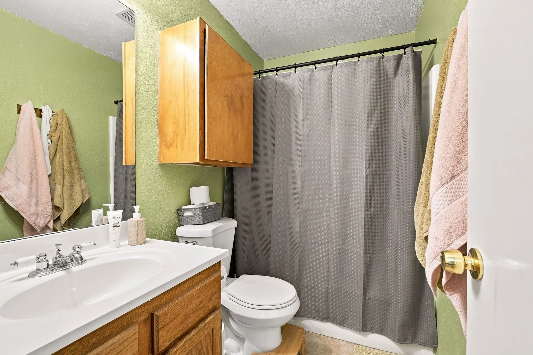 Full bathroom with a shower/tub combo, vanity, and a mirrored storage cabinet.
