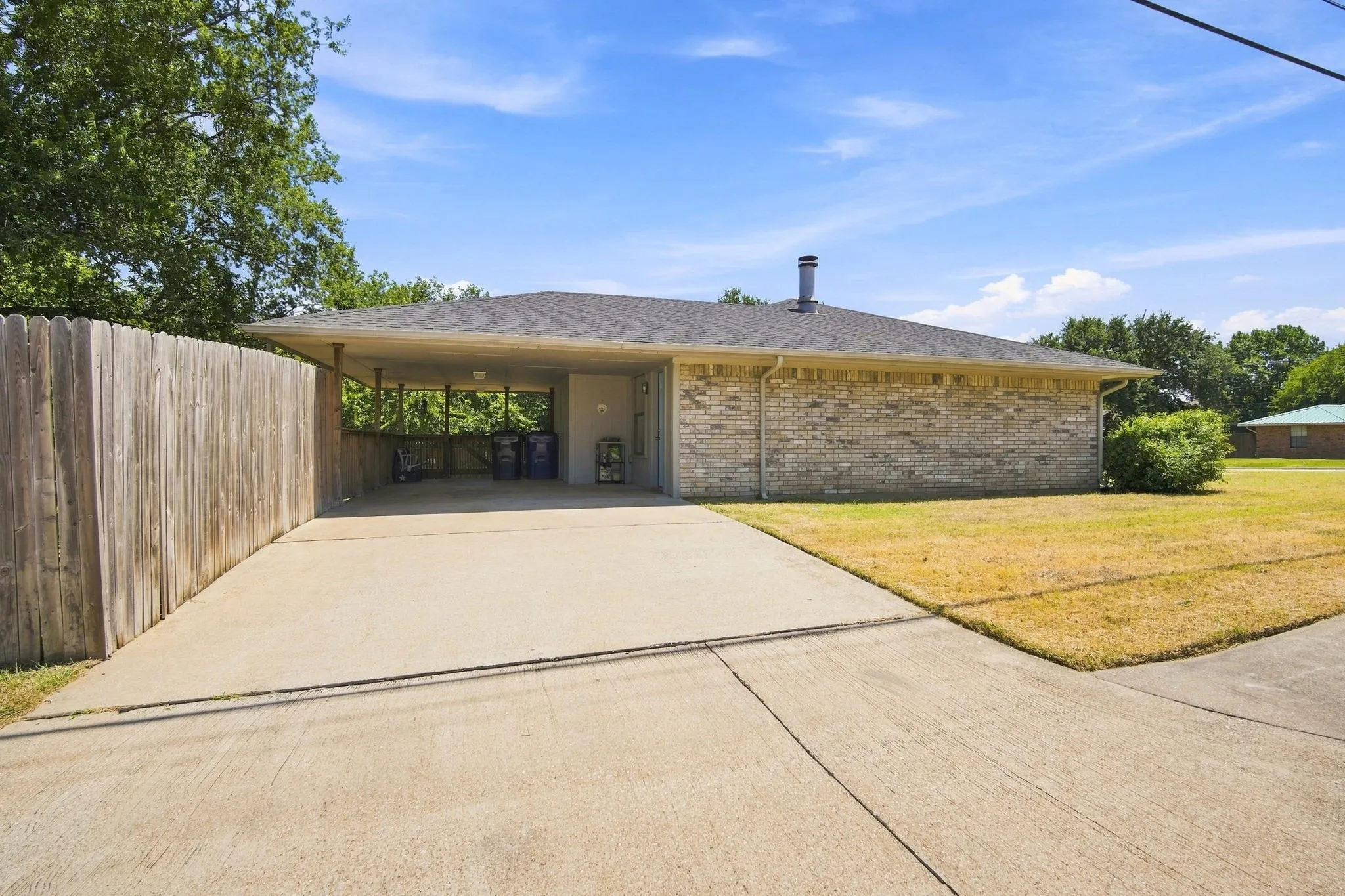 Side view of the home showcasing the carport and extended driveway, offering convenient parking.