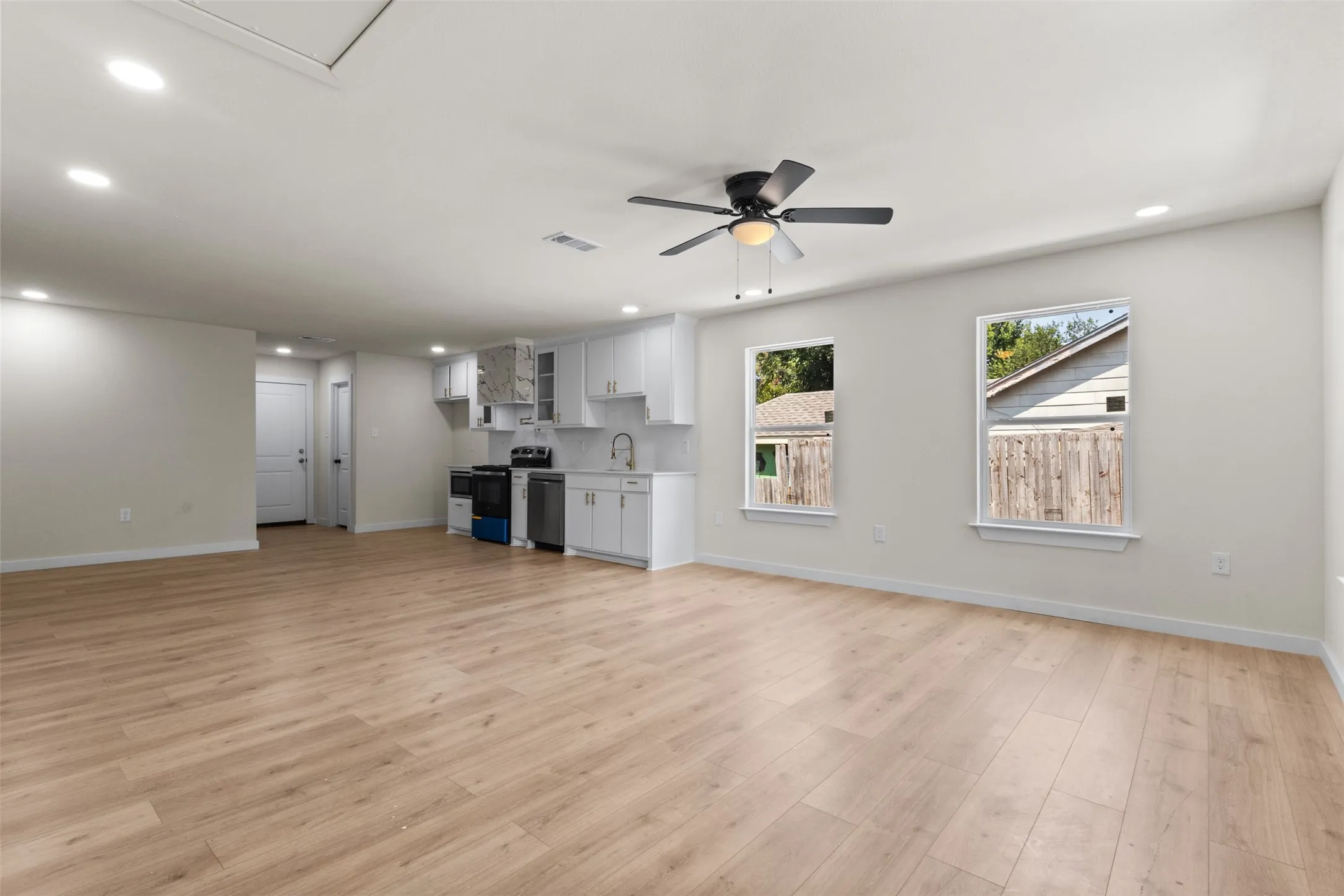 Open-concept living area featuring wood-finish flooring, recessed lighting, and a ceiling fan