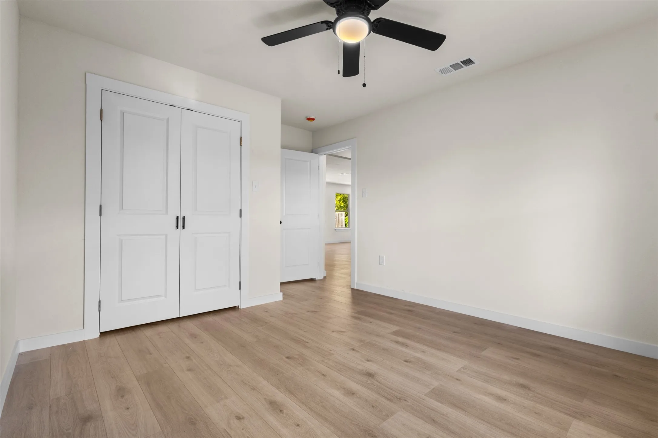 Room featuring light wood-finish flooring, white baseboards, and a neutral wall color