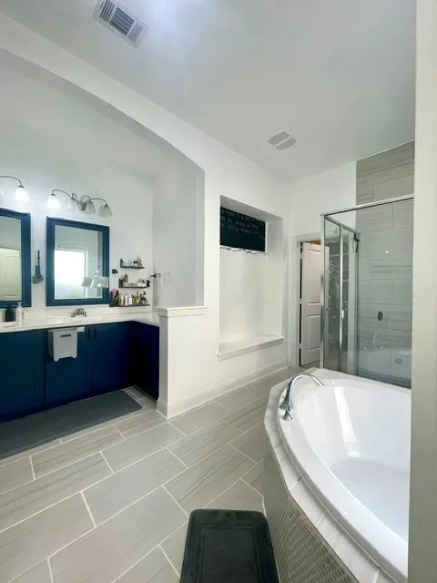 Primary bathroom dual mirror, dual sinks, bathtub, walk-in shower, sit-down area, closet entry