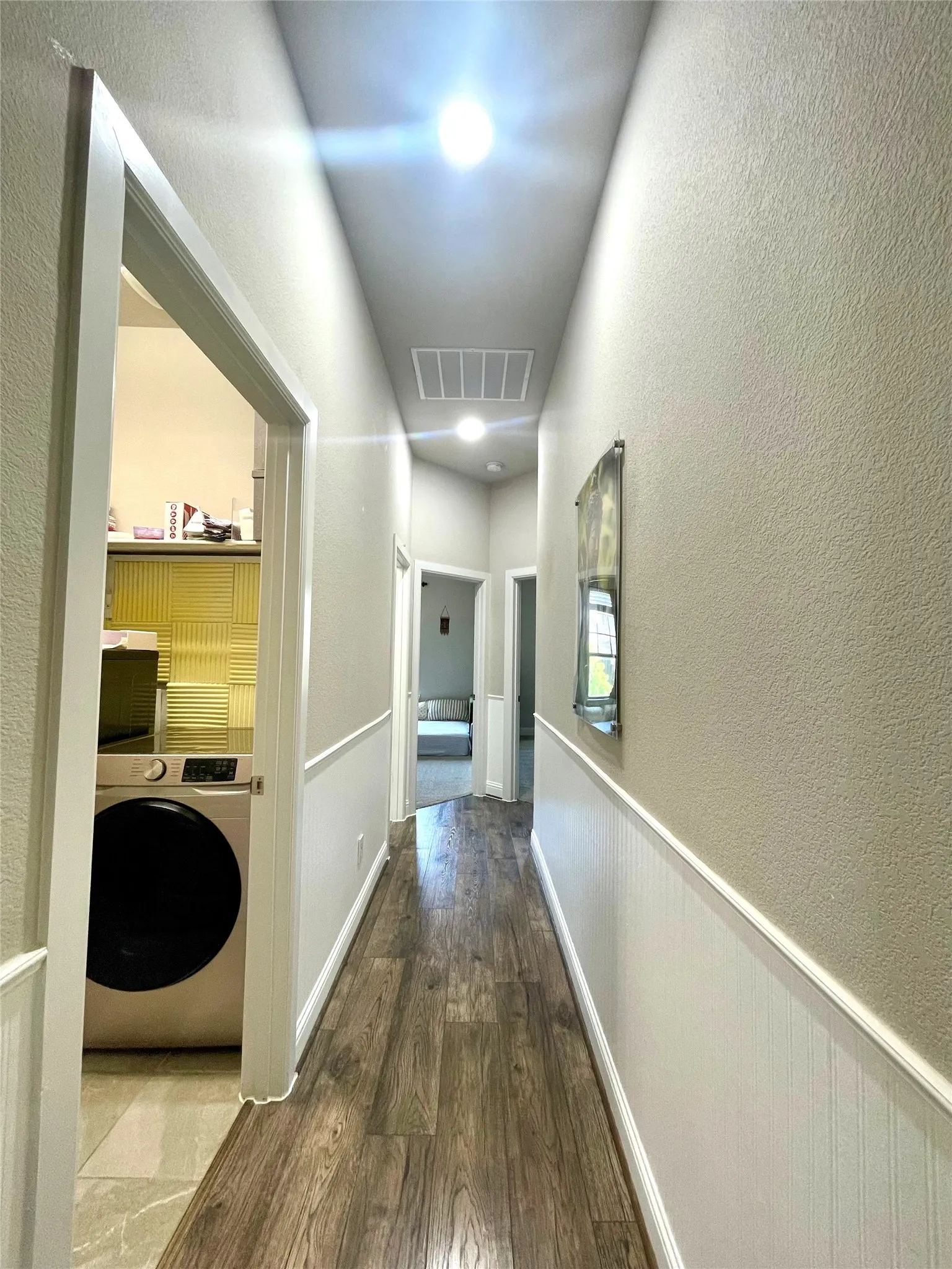 Hallway leading to utility room, full bathroom, secondary bedroom, third bedroom