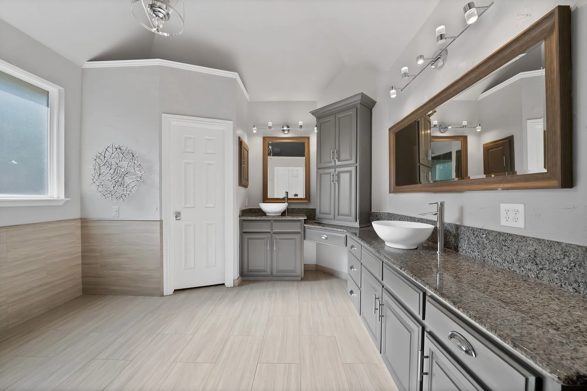 Spa-inspired primary bathroom featuring dual vanities with granite countertops, polished chrome fixtures, and an abundance of storage