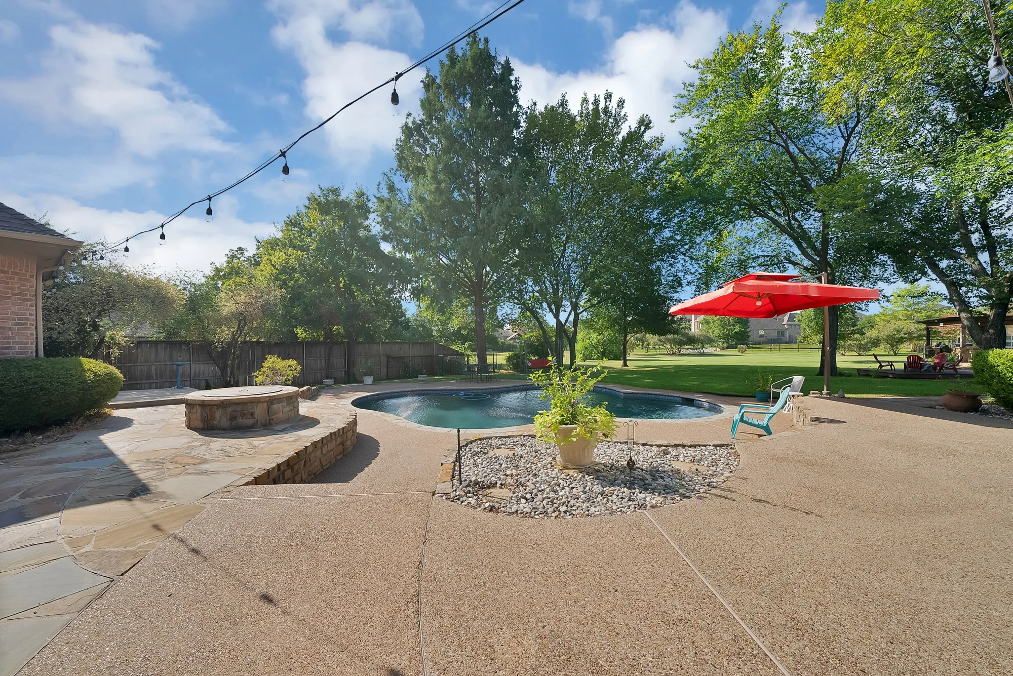 Resort-style backyard featuring a swimming pool, flagstone patio, built-in stone fire pit, and expansive lawn