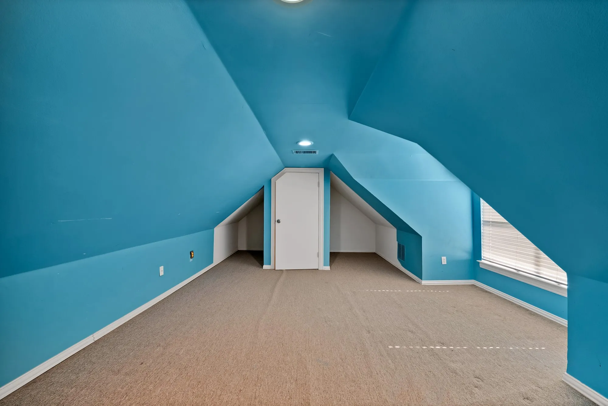 Bright attic room with dramatic vaulted ceilings and soft blue painted walls