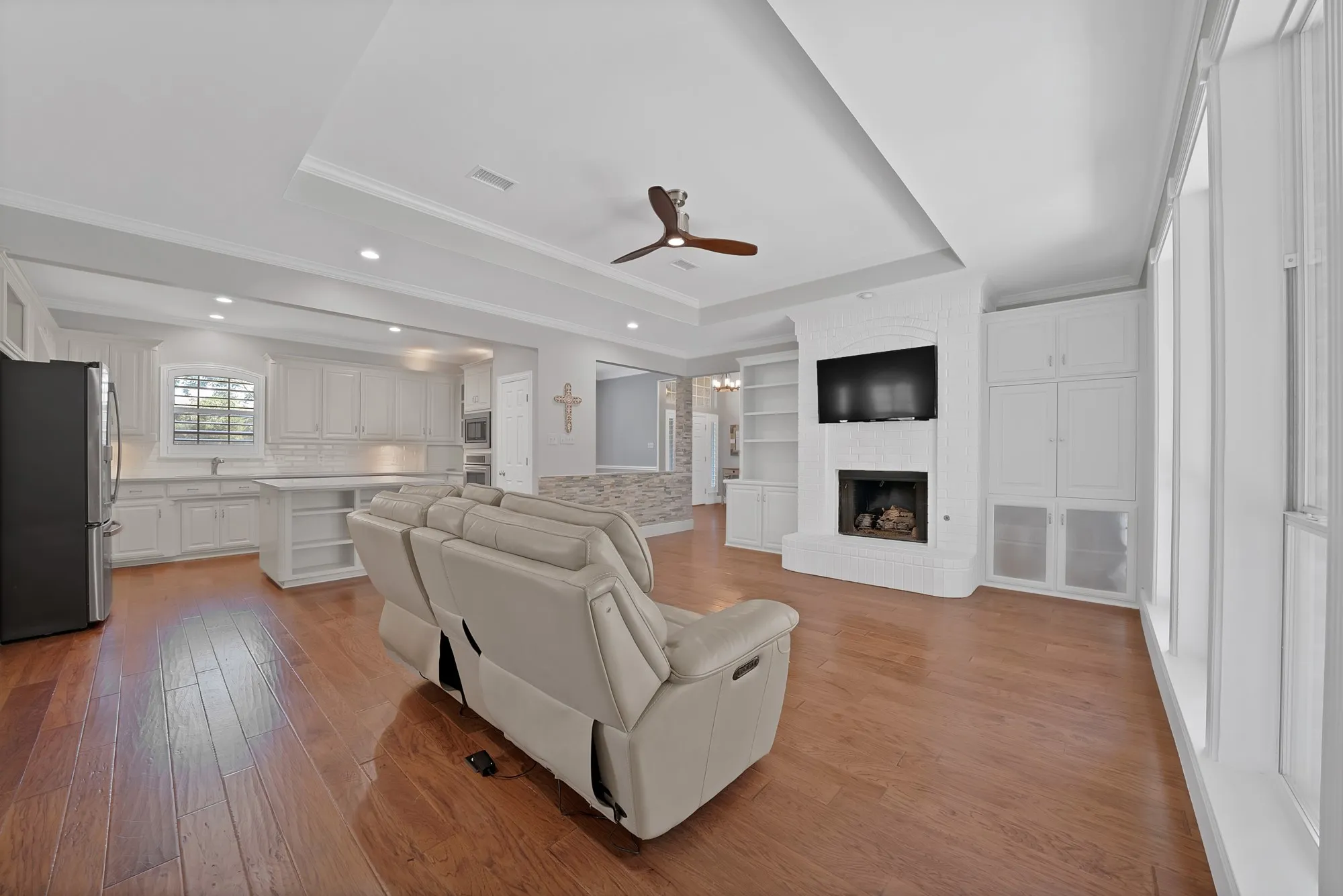Open-concept living area featuring rich wood-finish flooring and a tray ceiling