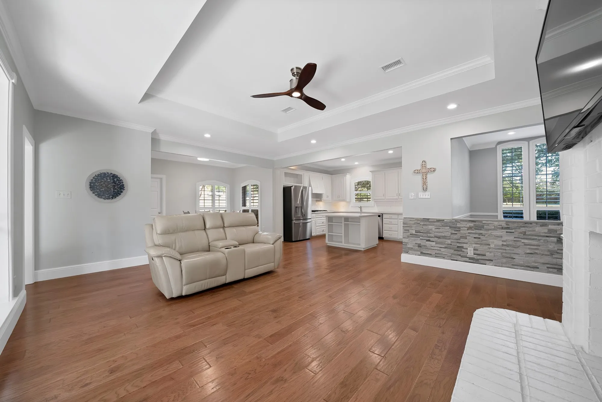 Open-concept living space featuring gleaming wood-finish flooring, recessed ceiling lighting, and a ceiling fan