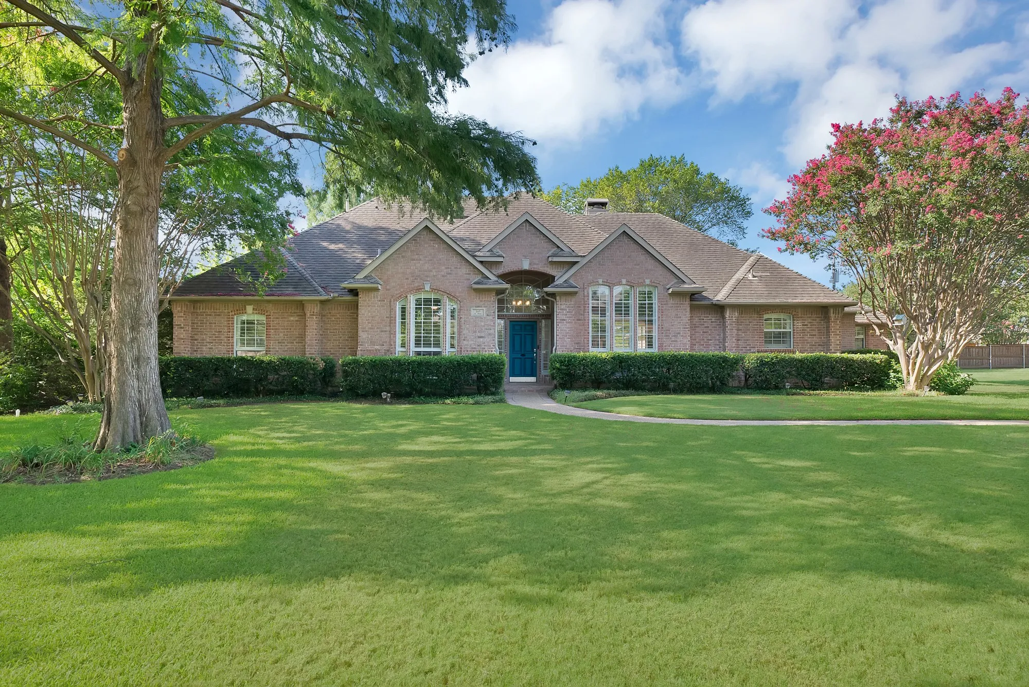 Traditional brick exterior with an arched entry and a prominent teal front door