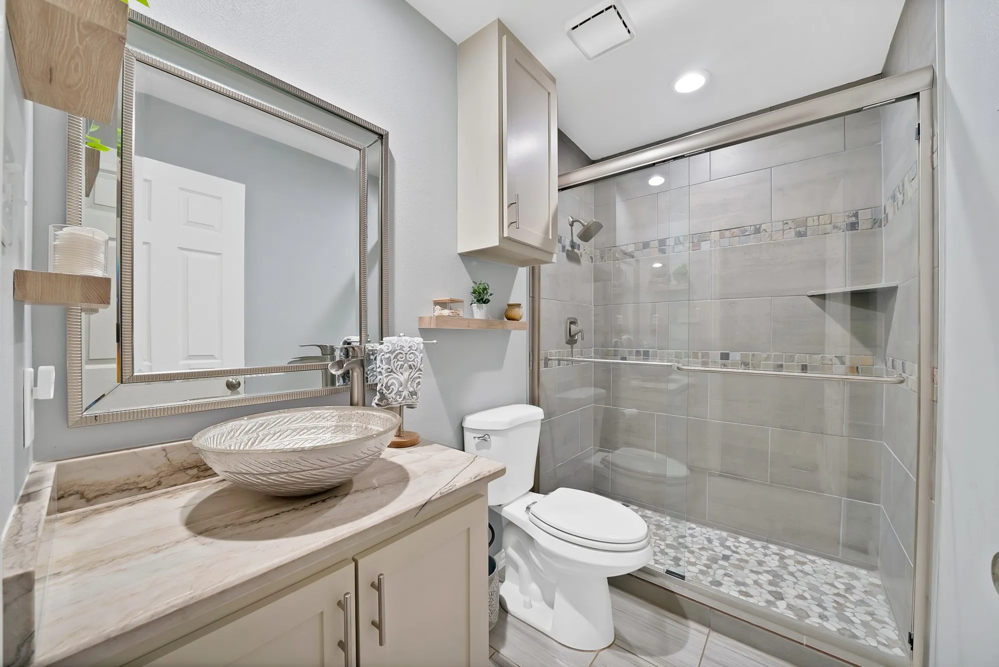 Spa-inspired primary bathroom featuring a floating wood-finish vanity with a round vessel sink, quartz countertop, and chrome fixtures