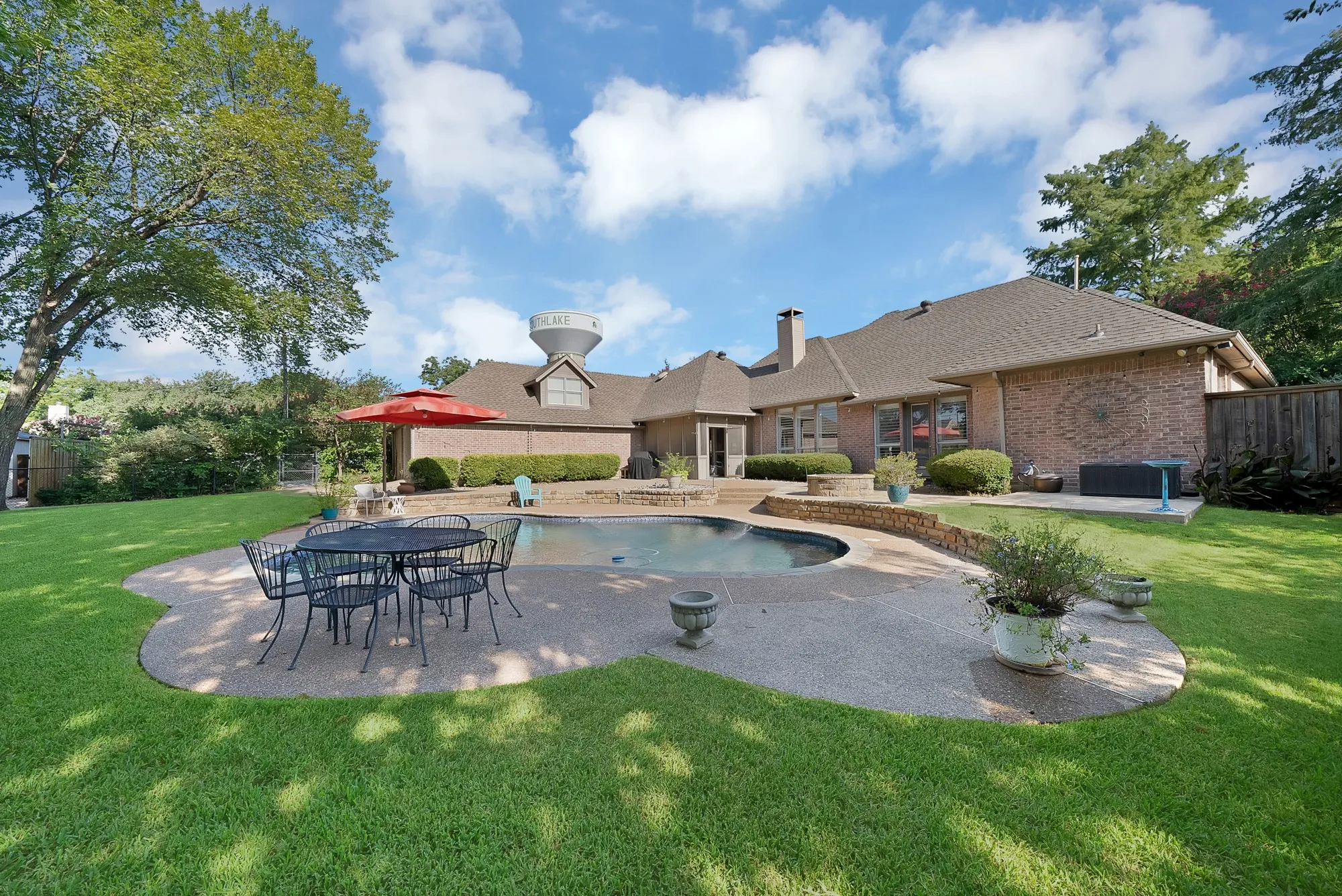Expansive backyard oasis featuring a resort-style free-form pool with curved edges, mature landscaping, and a manicured lawn