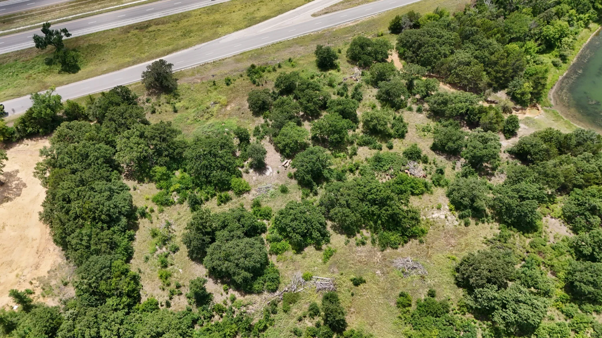 Expansive land parcel featuring mature tree coverage, natural clearings, and existing road frontage